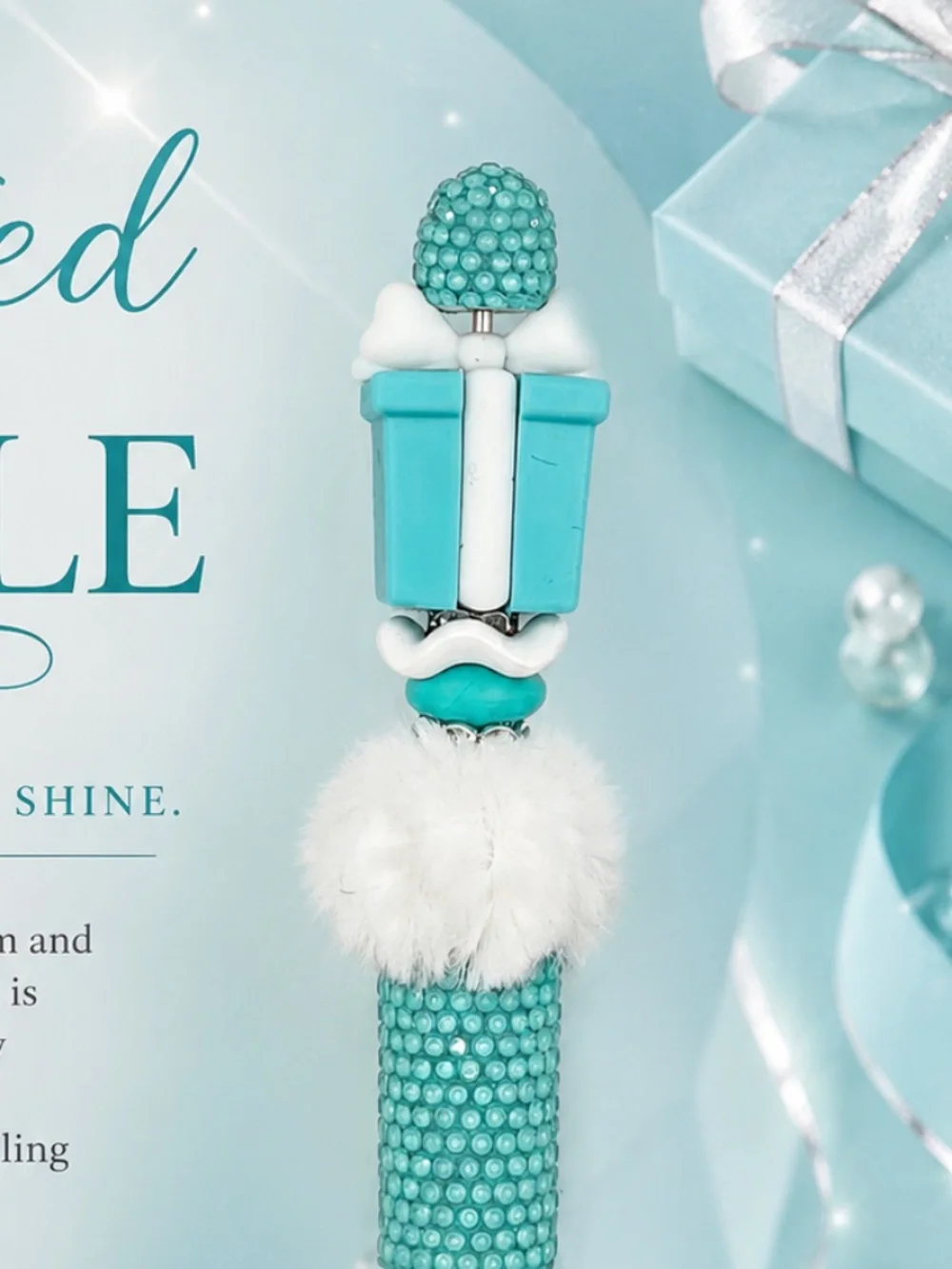 A cheerful aqua and white pen featuring a playful gift box topper, shimmering te
